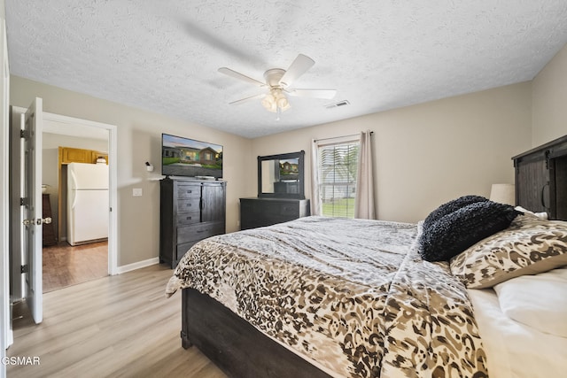 1733 Snapp Rd, Sevierville, TN 37862 - bedroom with freestanding refrigerator, light wood-style flooring, a ceiling fan, baseboards, and a textured ceiling