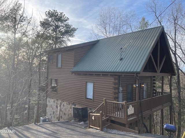 back of house featuring metal roof, stone siding, and log siding