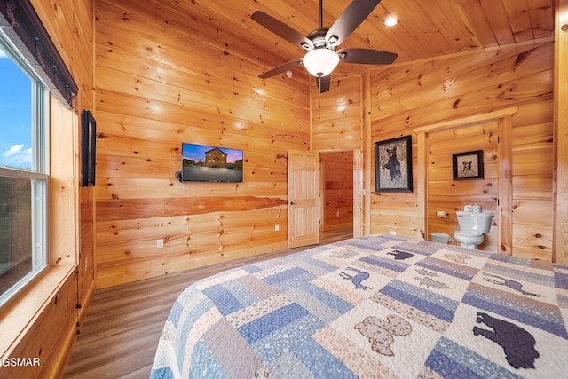 bedroom with ceiling fan, wooden ceiling, ensuite bathroom, wood-type flooring, and wooden walls