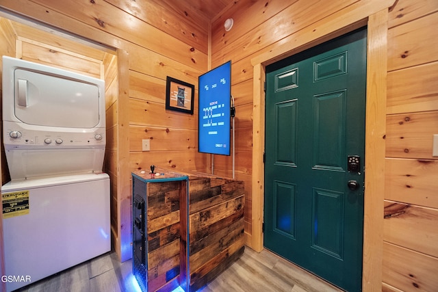 interior space featuring wood-type flooring, stacked washer and dryer, and wood walls