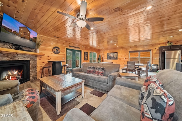 living room with a fireplace, ceiling fan, wood ceiling, and wood walls