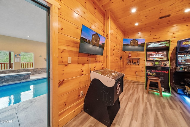 interior space with light hardwood / wood-style floors, wooden ceiling, and wood walls