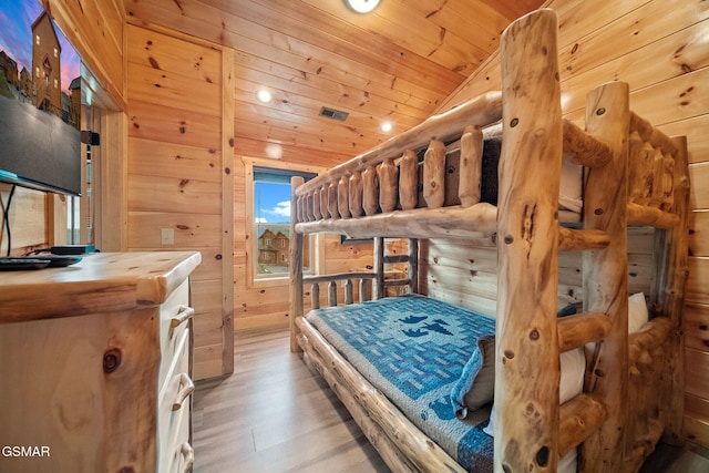 bedroom featuring hardwood / wood-style flooring, vaulted ceiling, wooden ceiling, and wood walls