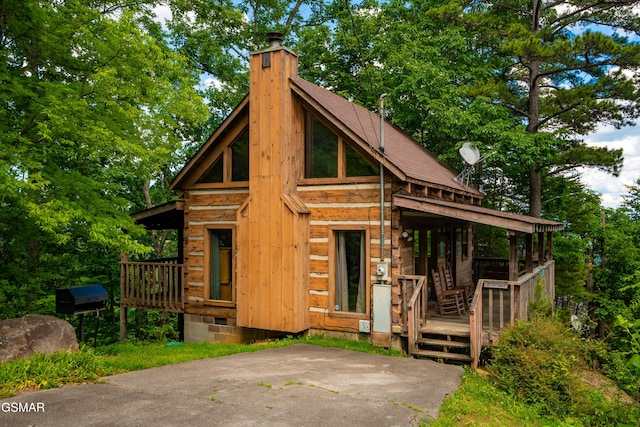 view of front of home with a chimney and roof with shingles