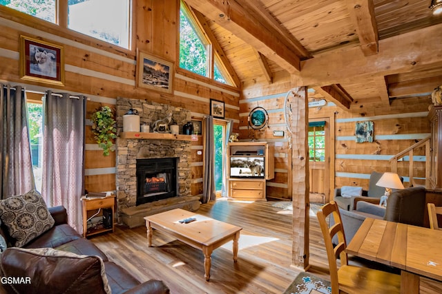 living room with wooden ceiling, wood walls, a stone fireplace, and beam ceiling