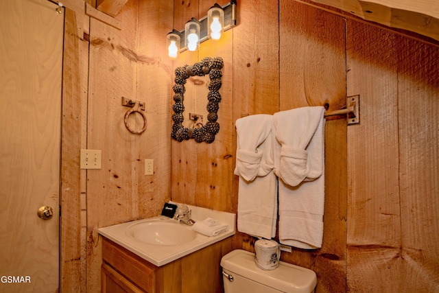 bathroom with wood walls, vanity, and toilet