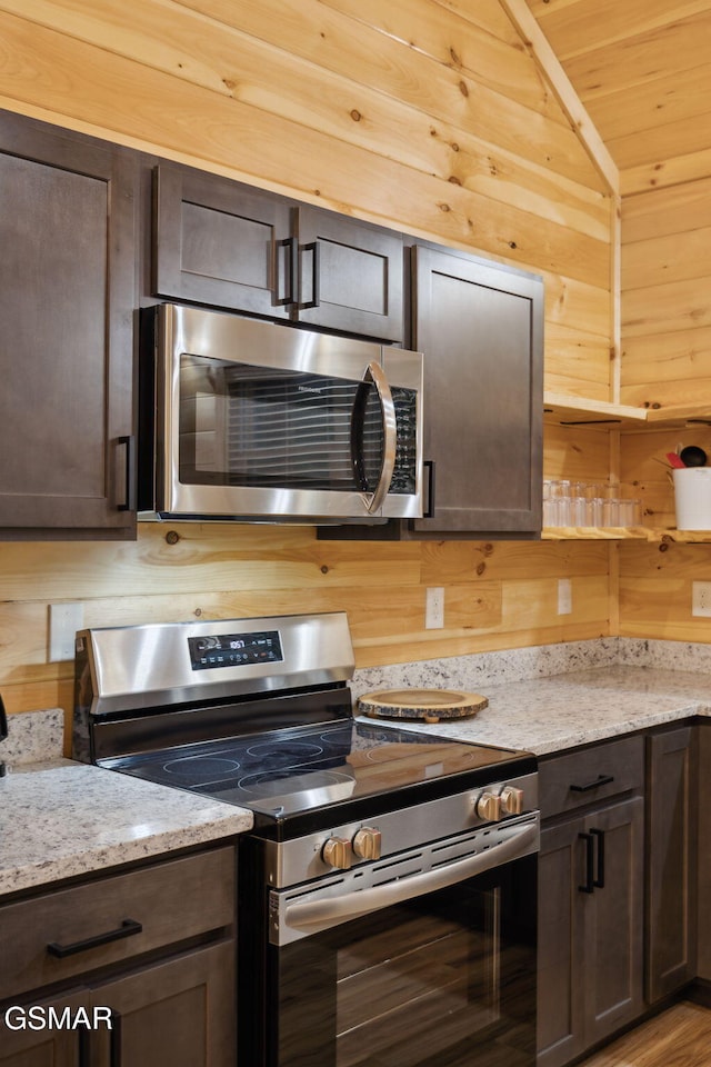 1010 Pinyon Cir, Pigeon Forge, TN 37863 - kitchen featuring stainless steel appliances, dark brown cabinetry, wooden walls, and light stone countertops
