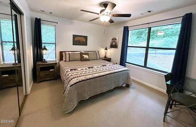 carpeted bedroom featuring baseboards, multiple windows, visible vents, and a textured ceiling