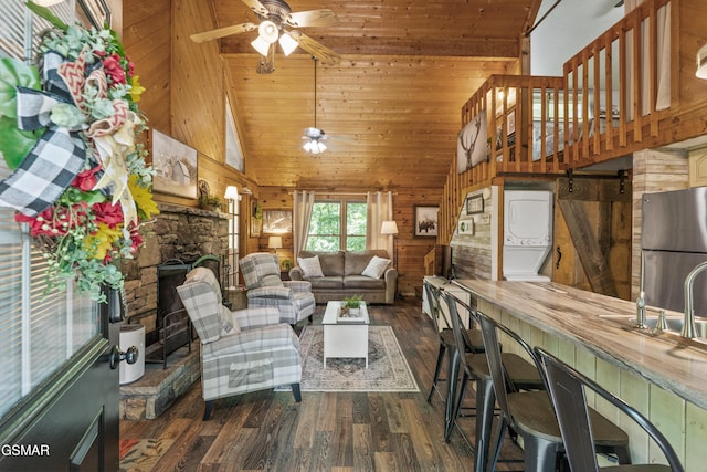 1514 Ridgecrest Dr, Sevierville, TN 37876 - living area with stacked washer and clothes dryer, high vaulted ceiling, wood-type flooring, ceiling fan, and wood walls