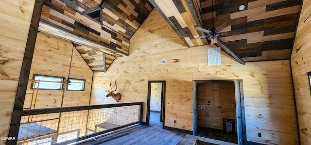 interior space featuring wooden walls, wood finished floors, and high vaulted ceiling