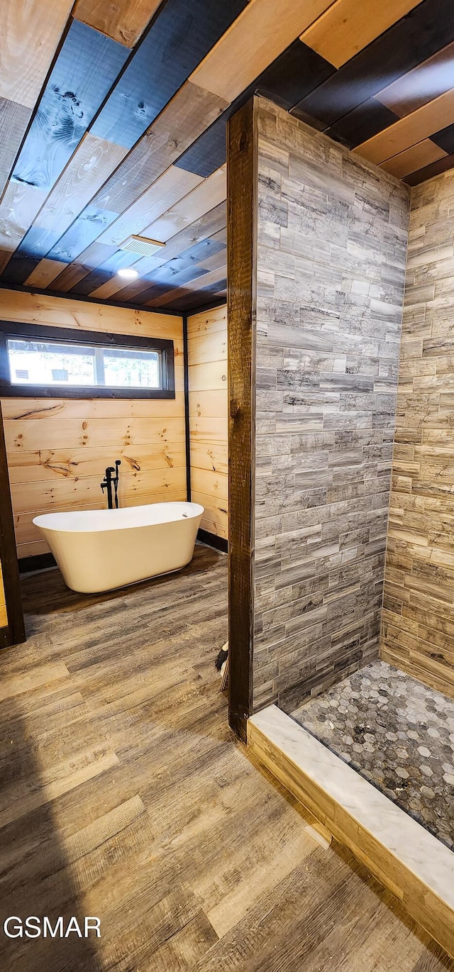 bathroom featuring tiled shower, a soaking tub, and wood finished floors