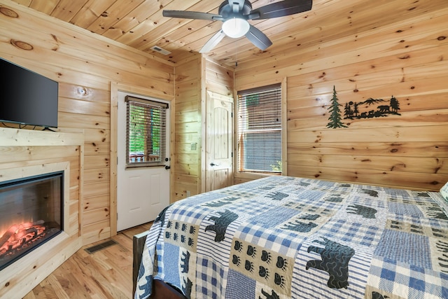 bedroom featuring wooden walls, hardwood / wood-style floors, ceiling fan, and wood ceiling