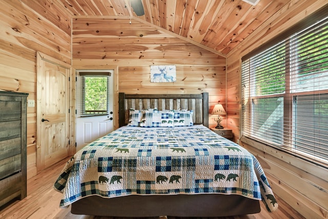 bedroom featuring wood walls, wood ceiling, light hardwood / wood-style flooring, and vaulted ceiling