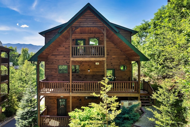 back of property with a mountain view and a balcony