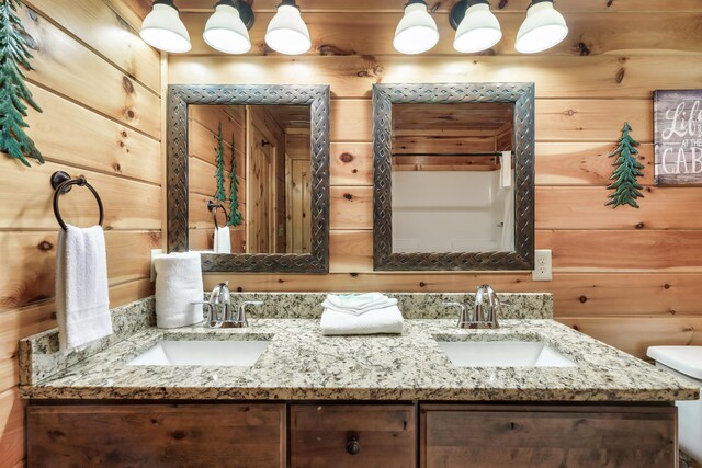 bathroom with vanity, toilet, and wooden walls