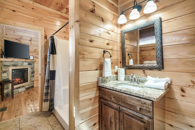 bathroom featuring wood ceiling, a shower with curtain, vanity, a fireplace, and wood walls