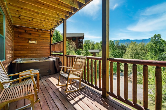 deck with a mountain view and a hot tub