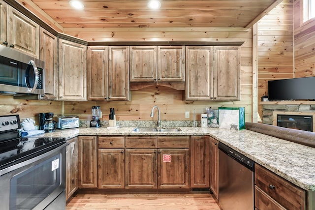 kitchen with sink, wood ceiling, stainless steel appliances, and wooden walls