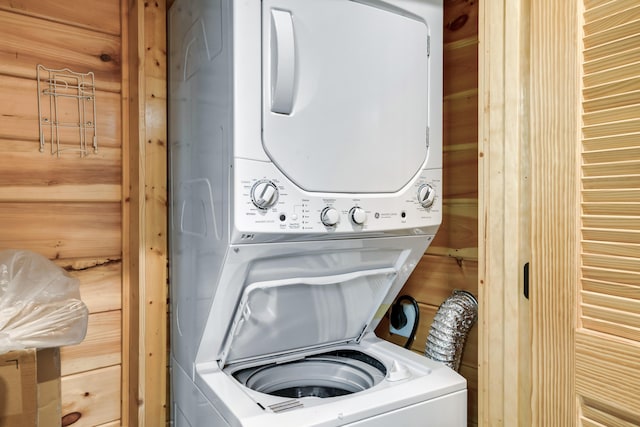 laundry room featuring stacked washer / dryer and wooden walls