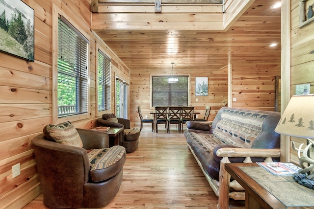 sitting room with a skylight, wooden ceiling, wooden walls, and light hardwood / wood-style flooring