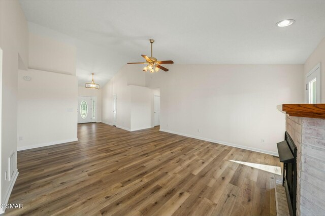 unfurnished living room featuring a fireplace, a wealth of natural light, vaulted ceiling, and ceiling fan