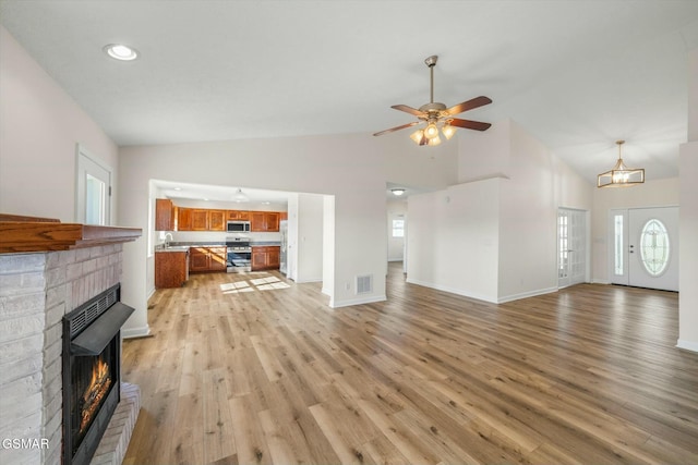 unfurnished living room featuring ceiling fan, a fireplace, a healthy amount of sunlight, and light hardwood / wood-style floors