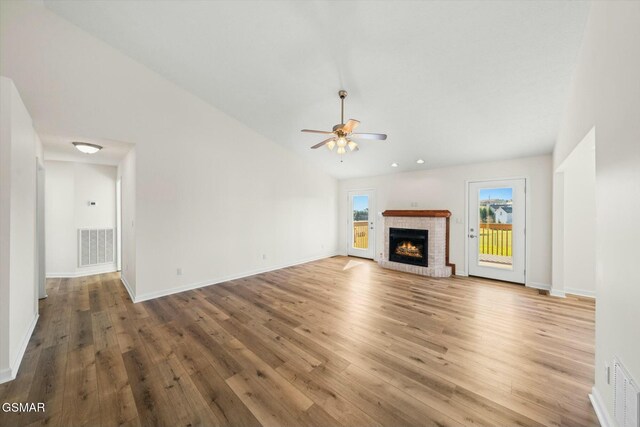 unfurnished living room featuring ceiling fan, a fireplace, vaulted ceiling, and hardwood / wood-style flooring