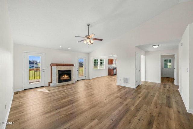 unfurnished living room featuring ceiling fan, wood-type flooring, high vaulted ceiling, and a brick fireplace