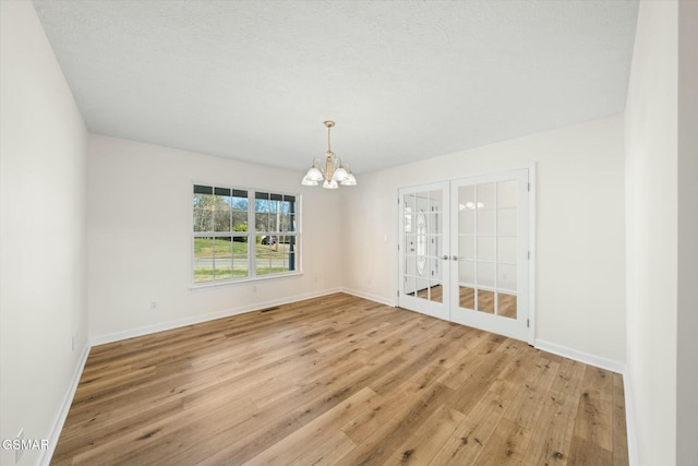 unfurnished room featuring light wood-type flooring and an inviting chandelier