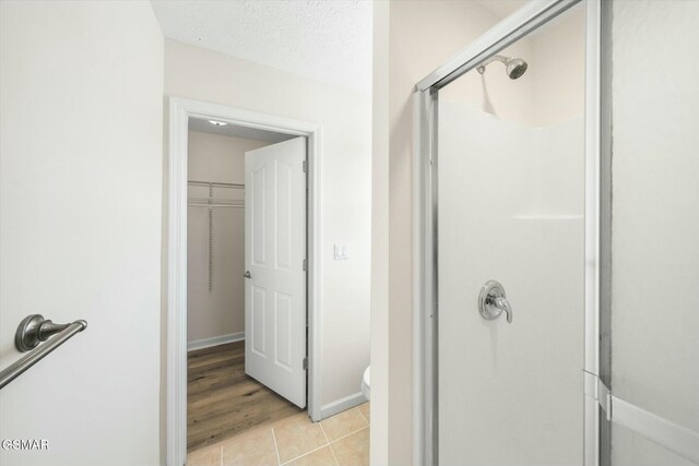 bathroom featuring tile patterned flooring, a shower with shower door, and a textured ceiling