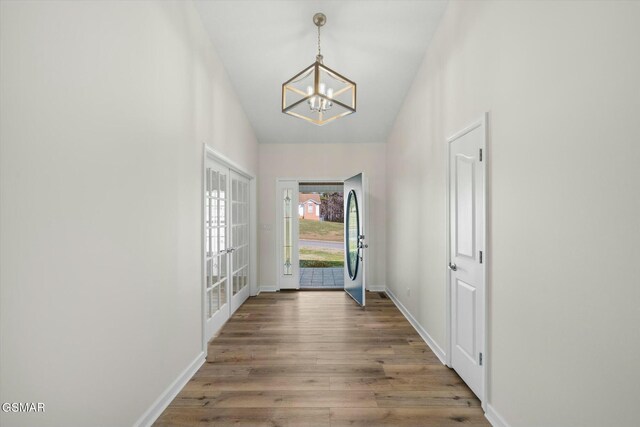 doorway with hardwood / wood-style floors, french doors, and a notable chandelier