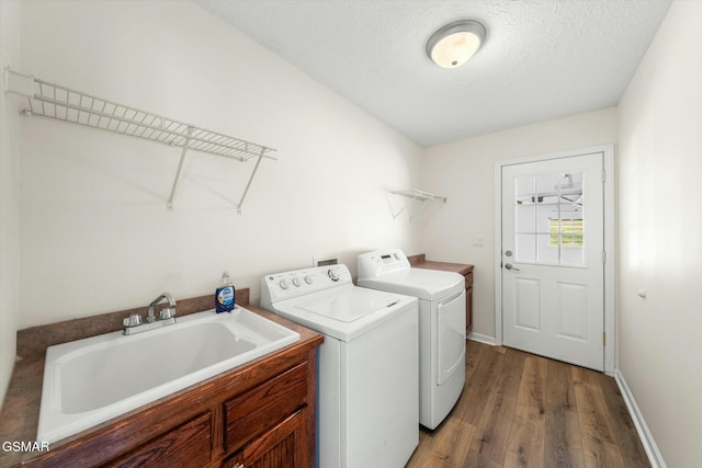 laundry area featuring sink, cabinets, separate washer and dryer, wood-type flooring, and a textured ceiling