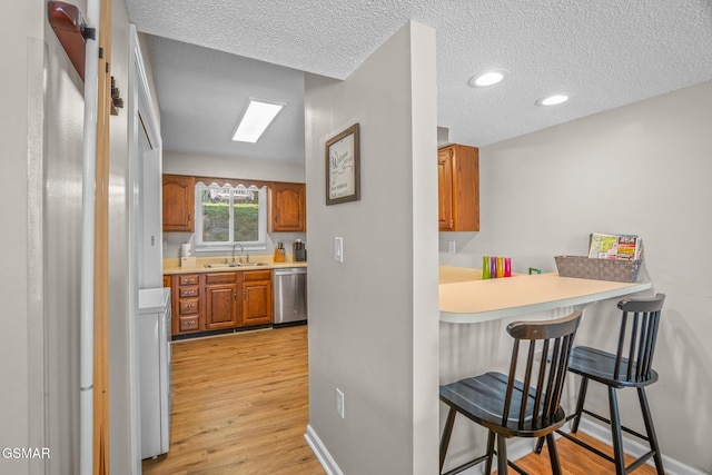 526 Briarcliff Way Apt 102, Pigeon Forge, TN 37863 - kitchen featuring dishwasher, brown cabinetry, a kitchen breakfast bar, light wood-style floors, and a textured ceiling