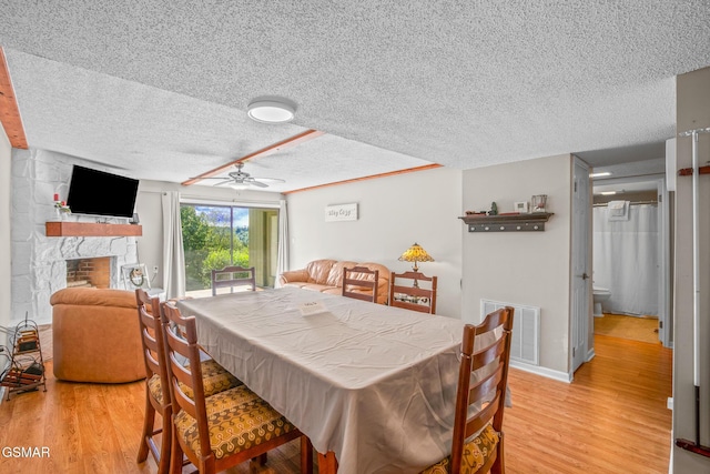 526 Briarcliff Way Apt 102, Pigeon Forge, TN 37863 - dining area with a textured ceiling, light wood finished floors, ceiling fan, and a stone fireplace