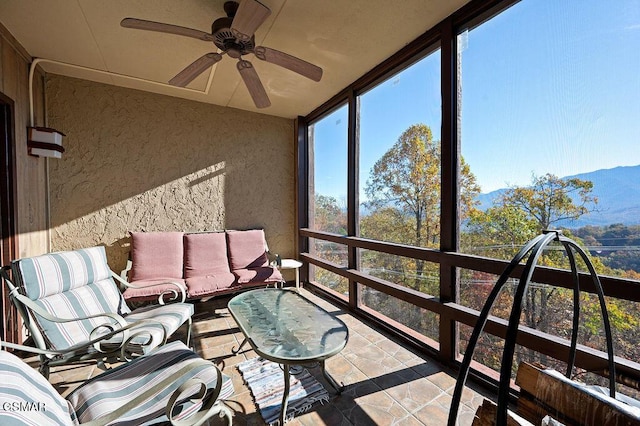 sunroom / solarium with ceiling fan and a mountain view