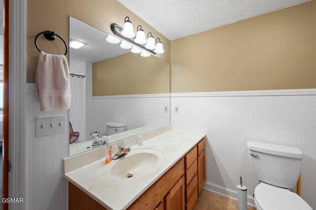 bathroom featuring tile patterned floors, vanity, a textured ceiling, and toilet