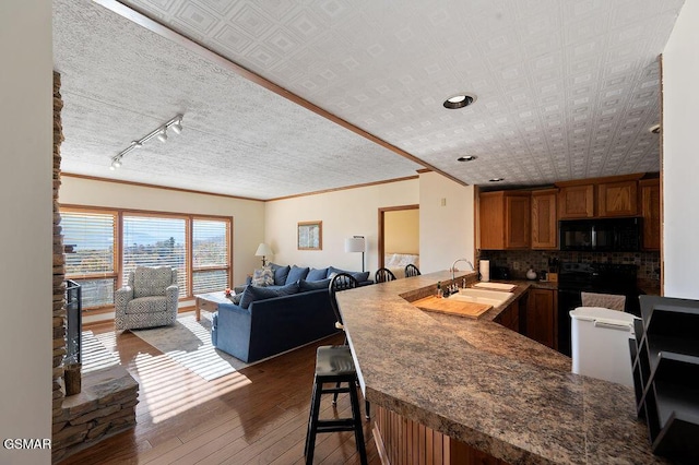 kitchen with tasteful backsplash, dark hardwood / wood-style floors, kitchen peninsula, a kitchen bar, and electric stove