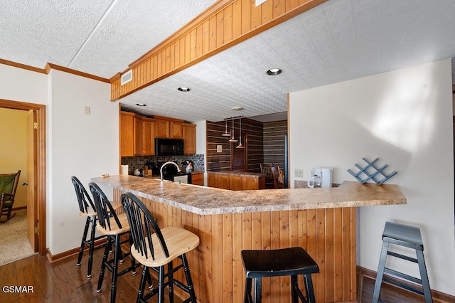 kitchen with electric range, a breakfast bar, dark hardwood / wood-style flooring, and kitchen peninsula