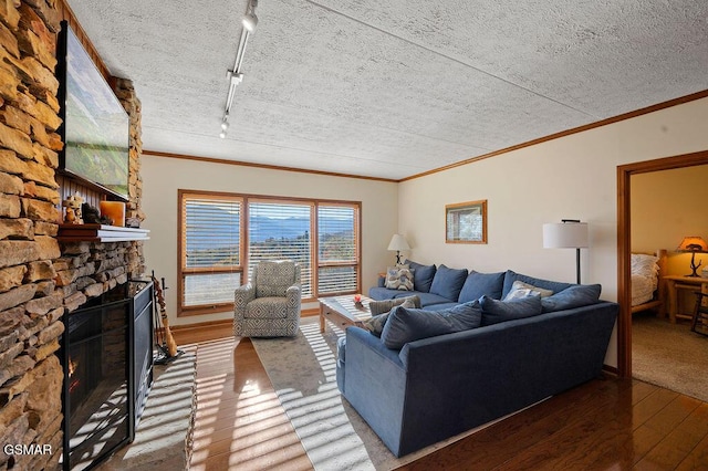 living room featuring track lighting, ornamental molding, a textured ceiling, a fireplace, and wood-type flooring