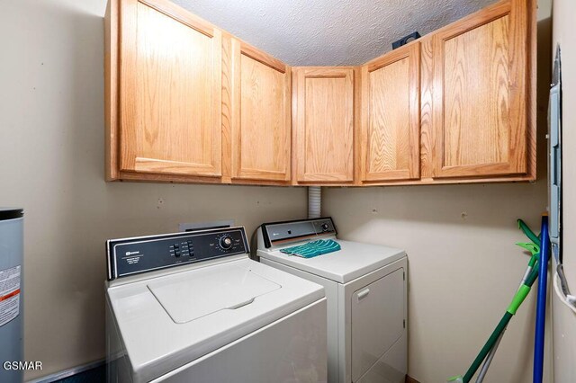 laundry area with cabinets, a textured ceiling, and independent washer and dryer