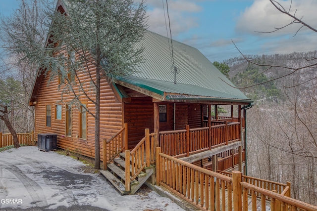 snow covered back of property featuring central AC and covered porch