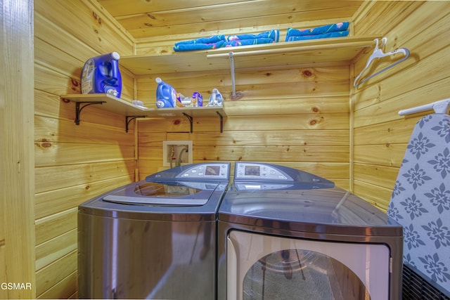 washroom with washing machine and dryer and wooden walls