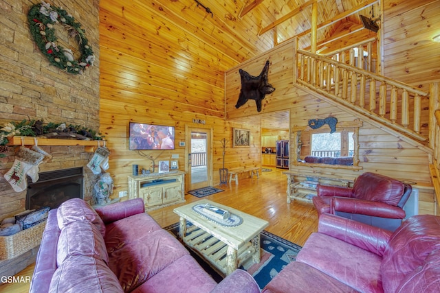 living room with wood walls, hardwood / wood-style floors, wooden ceiling, a fireplace, and high vaulted ceiling