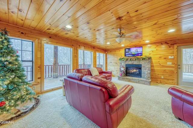 living room featuring ceiling fan, light colored carpet, a fireplace, and wooden walls