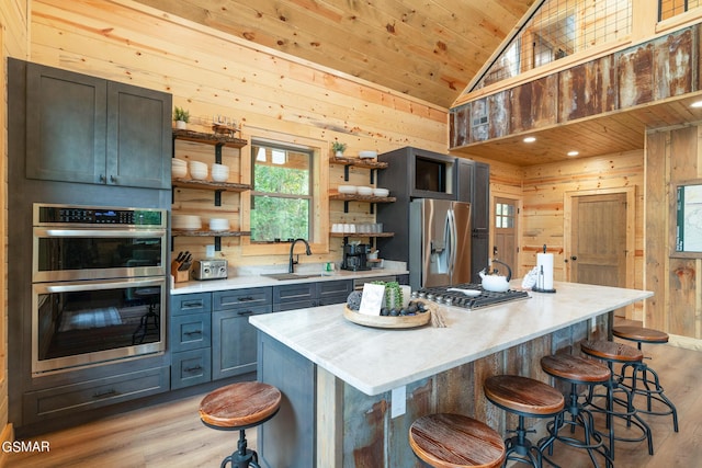 kitchen with wooden walls, a kitchen breakfast bar, sink, and appliances with stainless steel finishes