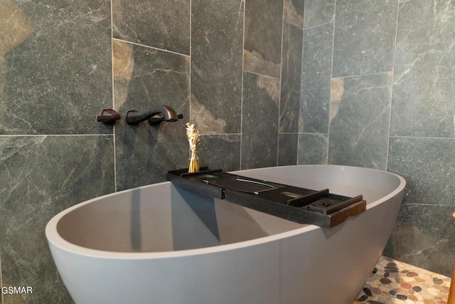 bathroom with a bathing tub, sink, and tile walls