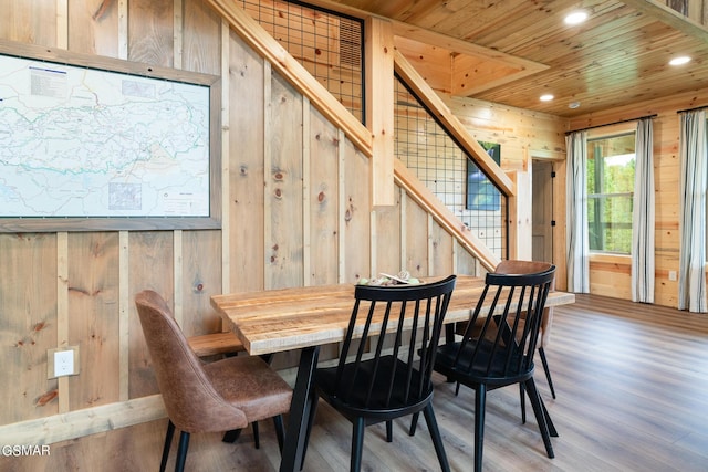 dining space featuring light wood-type flooring, wooden walls, and wood ceiling