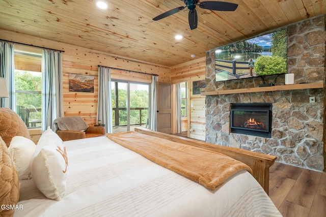 bedroom featuring wood walls, wood-type flooring, access to outside, a fireplace, and wood ceiling