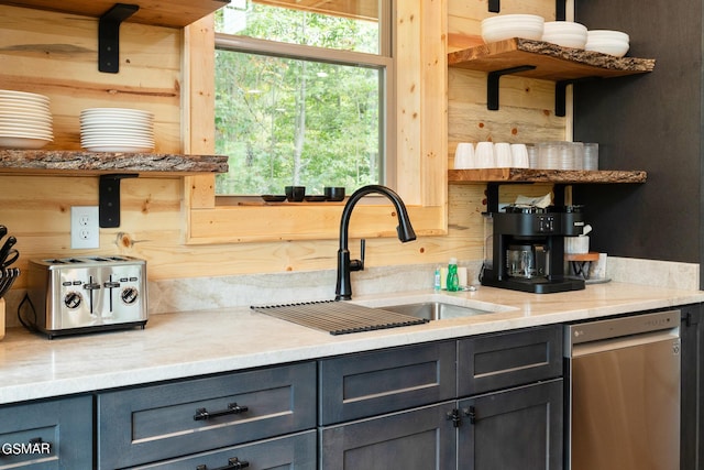 kitchen with dishwasher, light stone counters, wooden walls, and sink