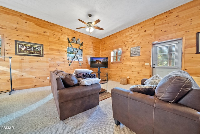 living room with light carpet, a textured ceiling, ceiling fan, and wood walls